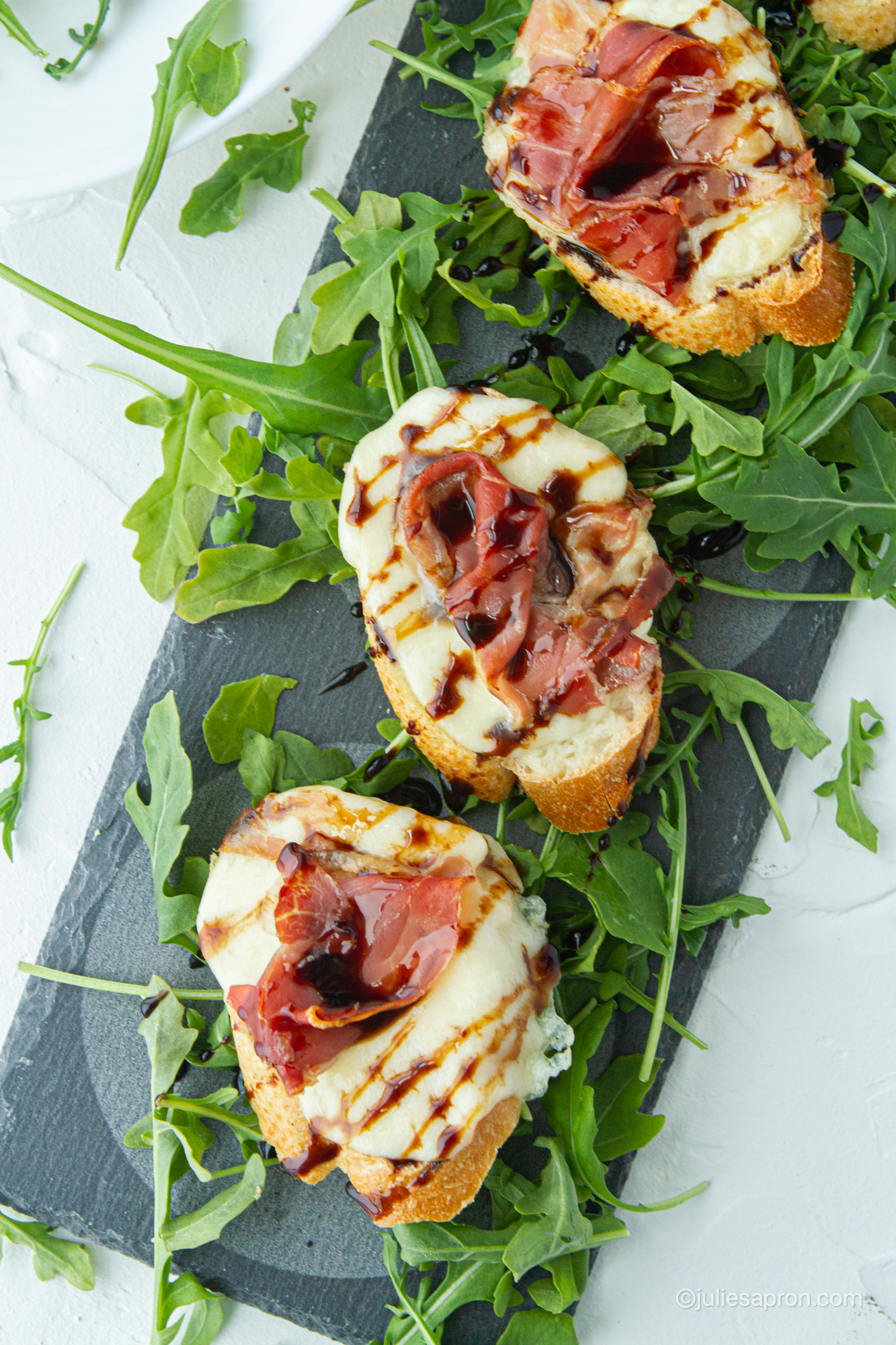 prosciutto melts on arugula on a serving plate