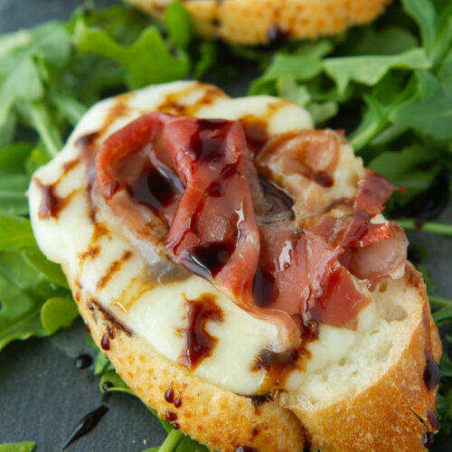 close up of prosciutto melts on arugula