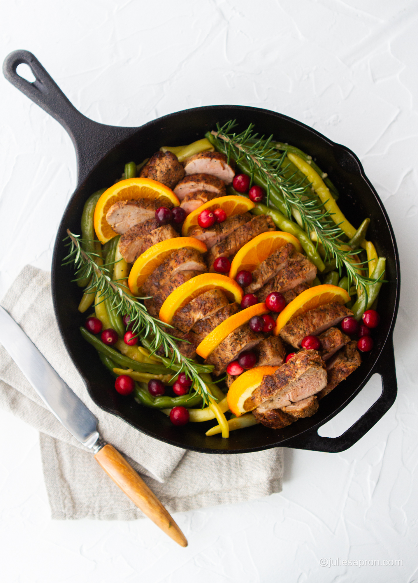 cast iron skillet with pork tenderloin and oranges and cranberries