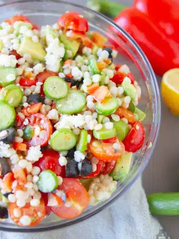 greek salad with cous cous in a glass bowl