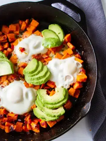 in a cast iron skillet sweet potatoes with eggs and avocado