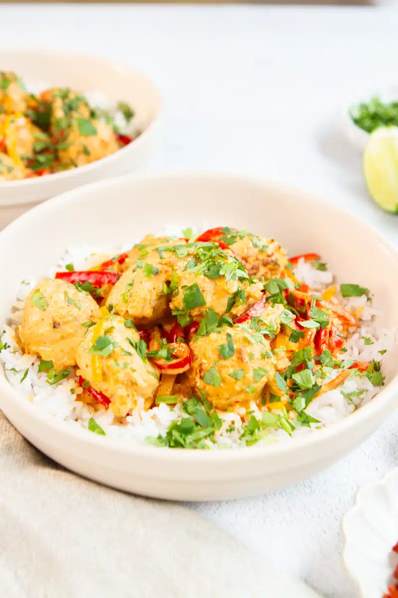 Thai coconut curry meatballs served hot with rice and garnished with lime wedges