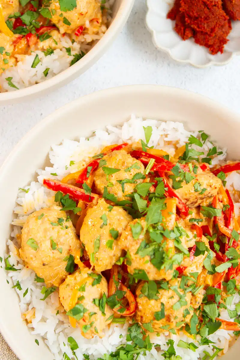 Homemade Thai coconut curry meatballs served in a bowl with vibrant red curry sauce