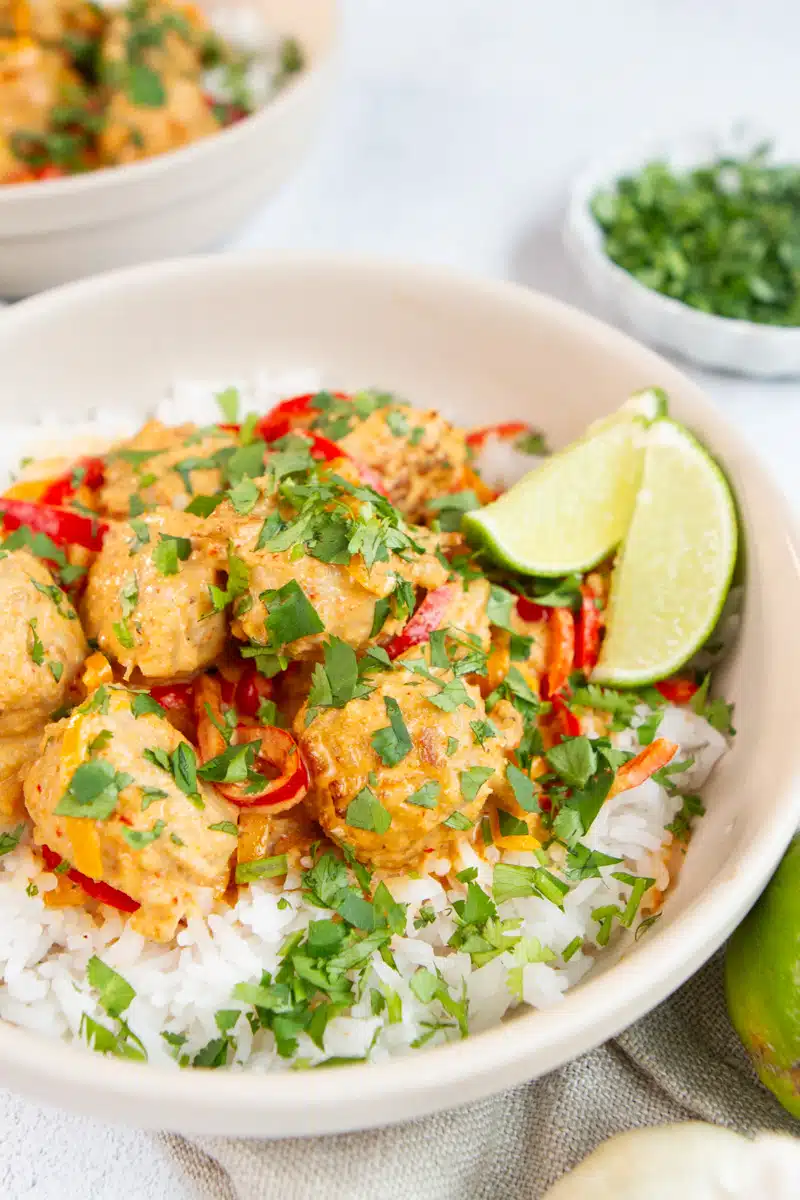 Juicy meatballs in rich Thai coconut curry sauce garnished with cilantro and lime