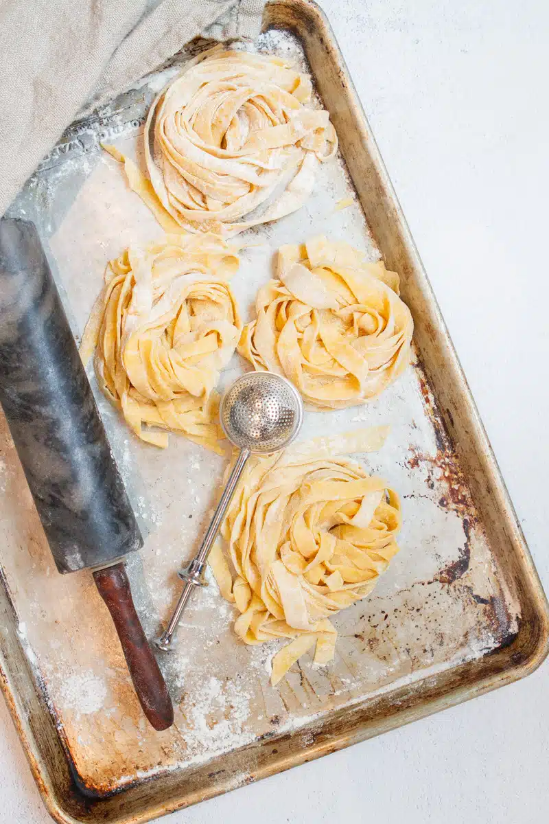 Homemade pasta without pasta machine ingredients styled on neutral background for easy from scratch recipe